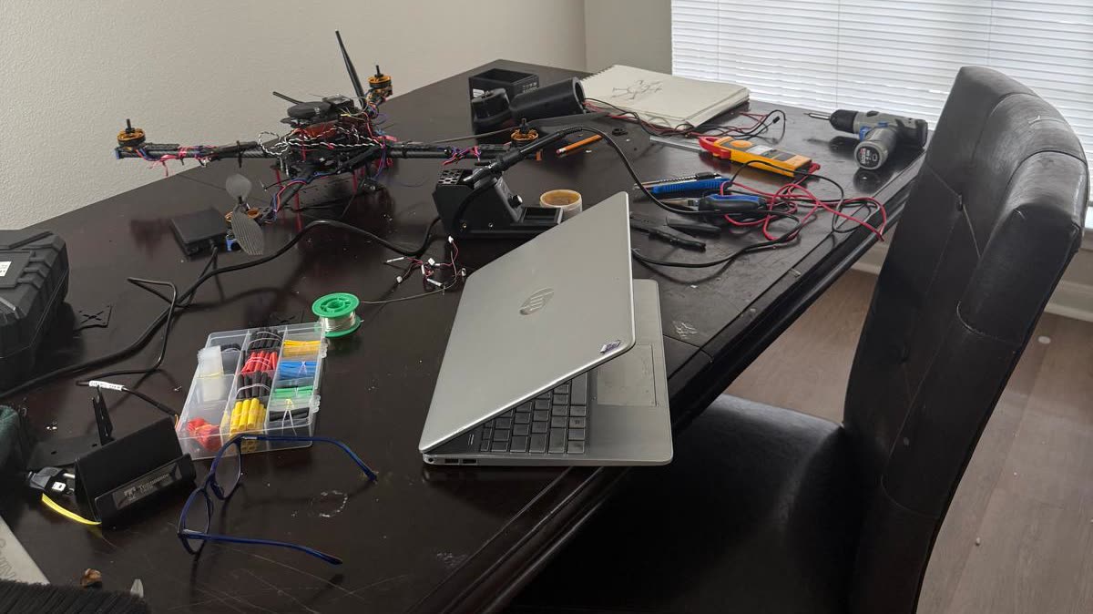 UAV airframe under construction on a workbench with tools, soldering iron and test equipment
